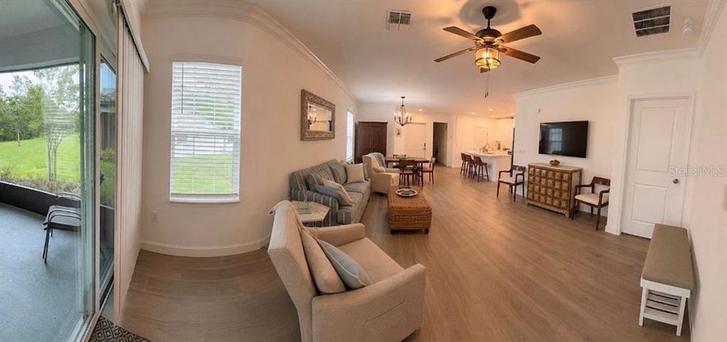 A bright, open-concept living and dining area features light wood flooring and a ceiling fan — 16890 FORGE SURF STREET, LAND O LAKES, FL