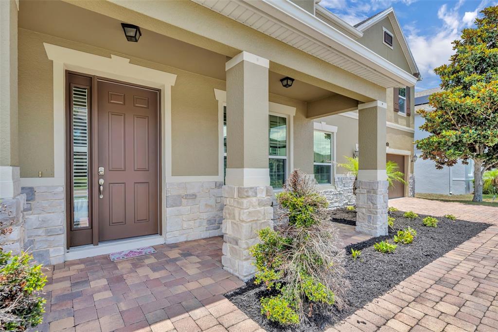 A front porch with a brown door, stone accents, and a paved walkway — 14001 RUGBY STREET, OAKLAND, FL