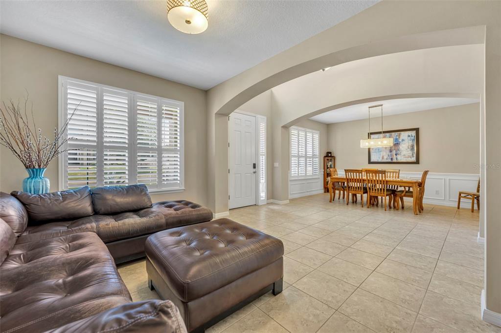 A living room with a leather sectional and ottoman flows into a dining area — 14001 RUGBY STREET, OAKLAND, FL