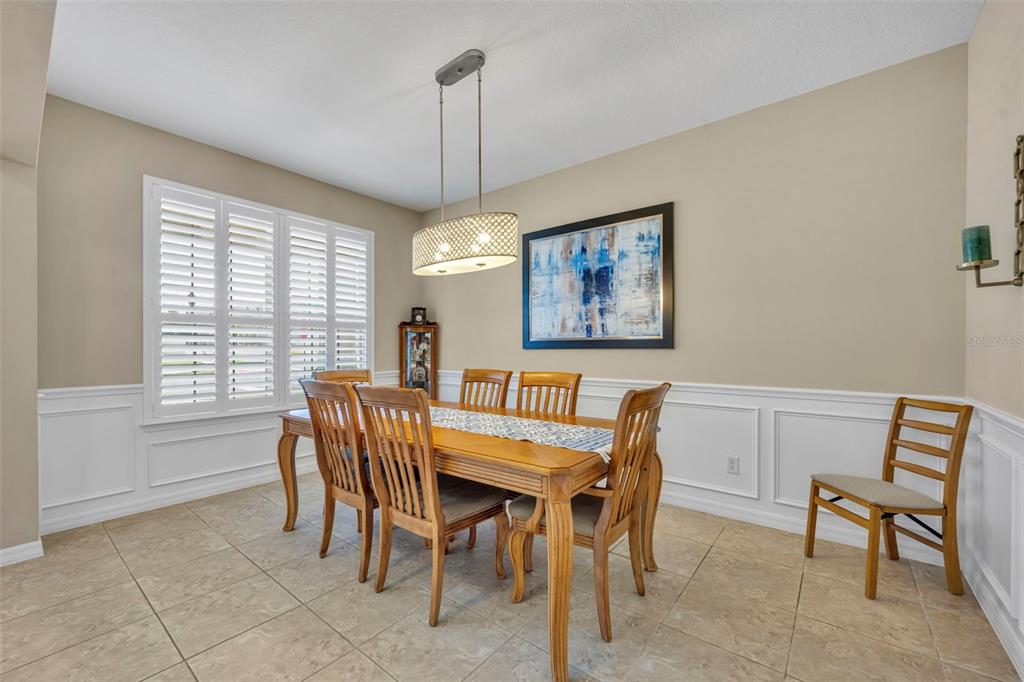 A dining room features a wooden table with six chairs, wainscoting, and a pendant light — 14001 RUGBY STREET, OAKLAND, FL