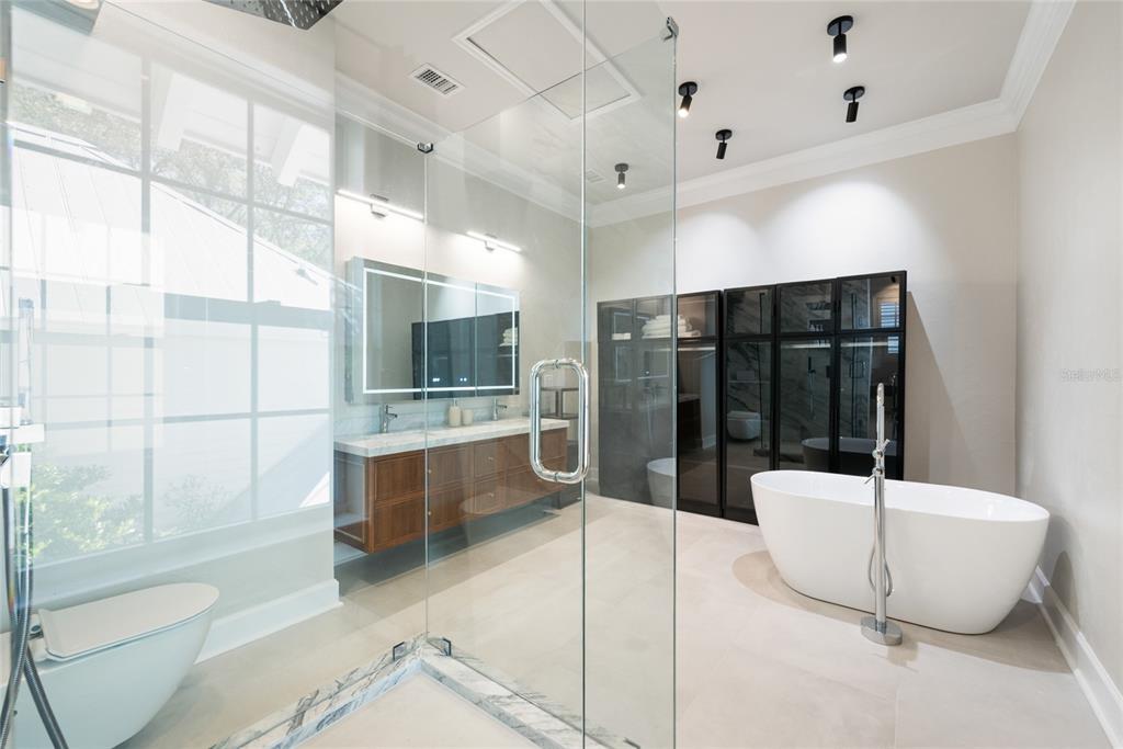 A modern bathroom features a glass-enclosed shower, a freestanding tub, and a double-sink wood vanity — 5043 SW 91 DRIVE, GAINESVILLE, FL