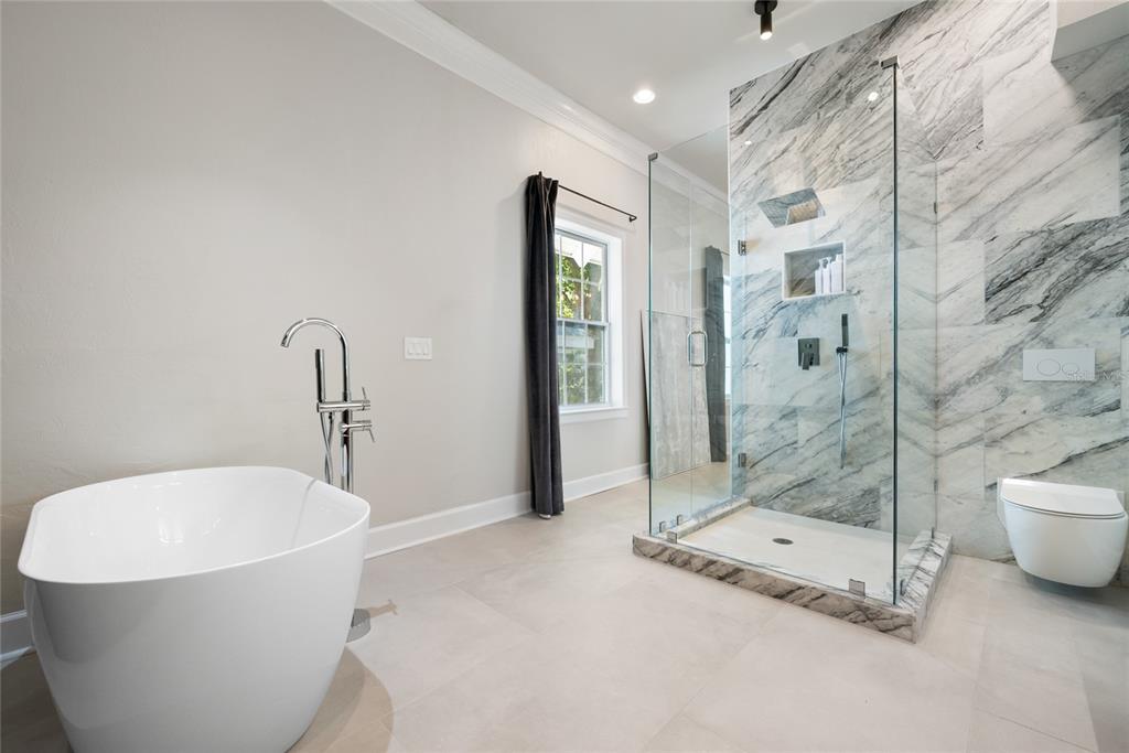A modern bathroom features a freestanding tub, a glass-enclosed marble shower, and a wall-mounted toilet — 5043 SW 91 DRIVE, GAINESVILLE, FL