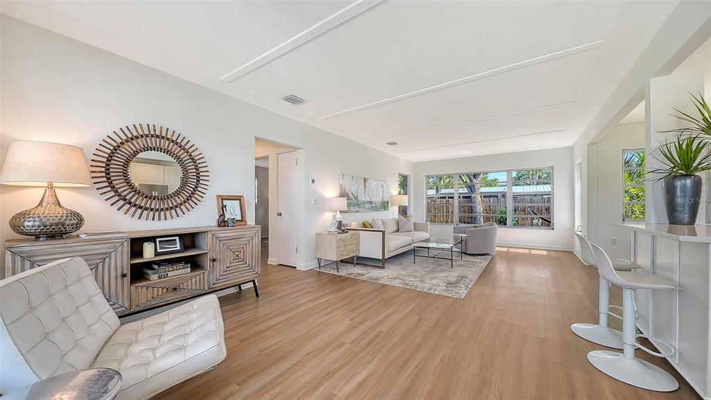 A bright living room features wood-look flooring, a white sofa, and a modern sideboard — 2719 TEMPLE STREET, SARASOTA, FL