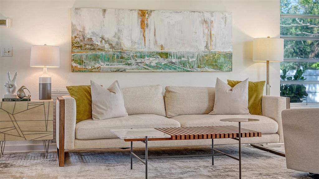 A living room features a beige sofa, a slatted coffee table, and abstract wall art — 2719 TEMPLE STREET, SARASOTA, FL
