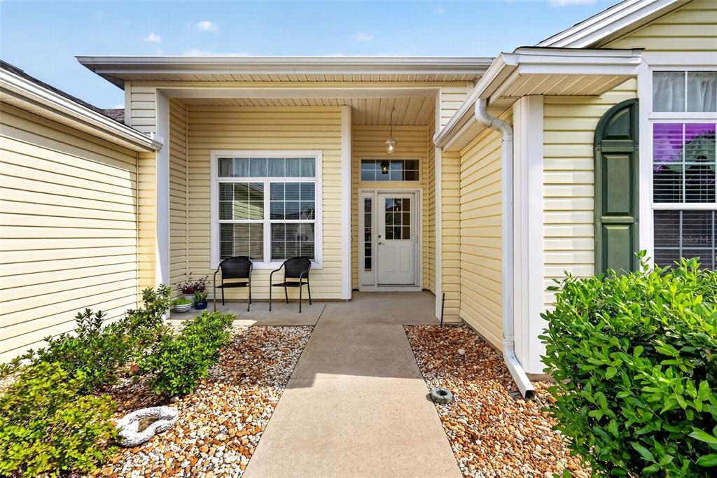 A concrete walkway leads to the front entrance of a yellow house with siding — 2234 WESTCHESTER WAY, THE VILLAGES, FL