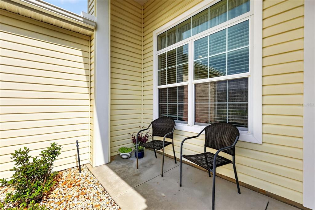 A small concrete porch features two dark wicker chairs and a potted plant — 2234 WESTCHESTER WAY, THE VILLAGES, FL