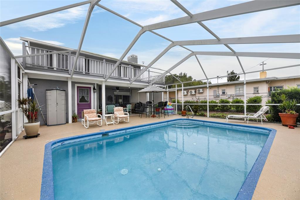 A screened-in swimming pool sits on a patio behind a two-story house — 3312 N LAKE DRIVE, PLANT CITY, FL