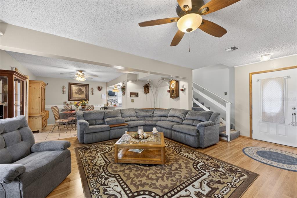 A living room features a large gray sectional sofa, wood flooring, and a ceiling fan — 3312 N LAKE DRIVE, PLANT CITY, FL