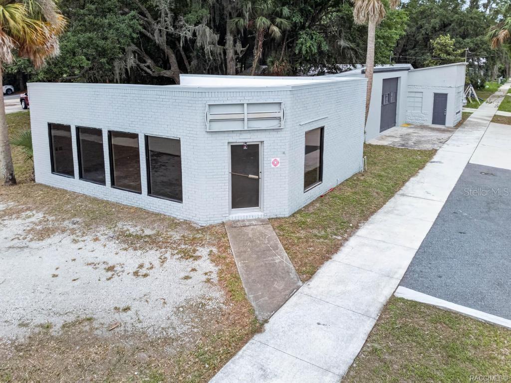 An exterior view of a single-story, light gray painted brick commercial building with large windows — 1321 SAINT JOHNS AVENUE, PALATKA, FL