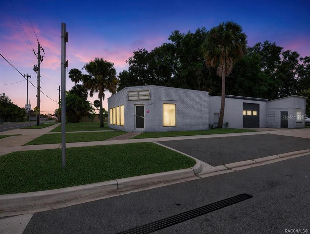 A single-story white brick commercial building sits on a corner lot at sunset — 1321 SAINT JOHNS AVENUE, PALATKA, FL