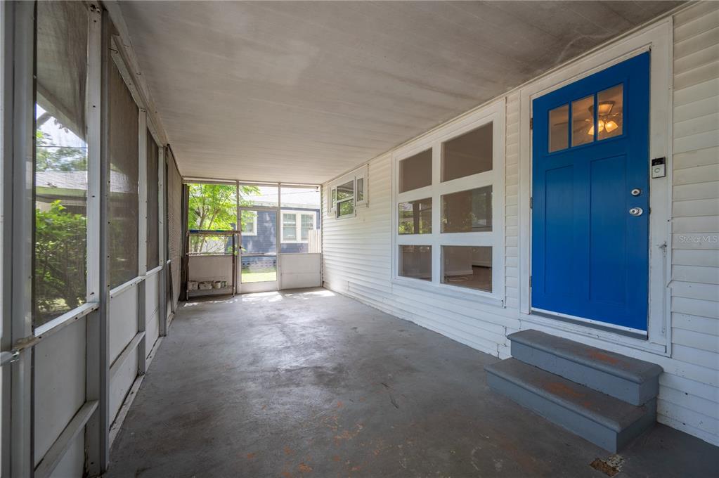 A virtually staged covered porch features a seating area, a blue door, and screen walls — 714 W BELMAR STREET, LAKELAND, FL
