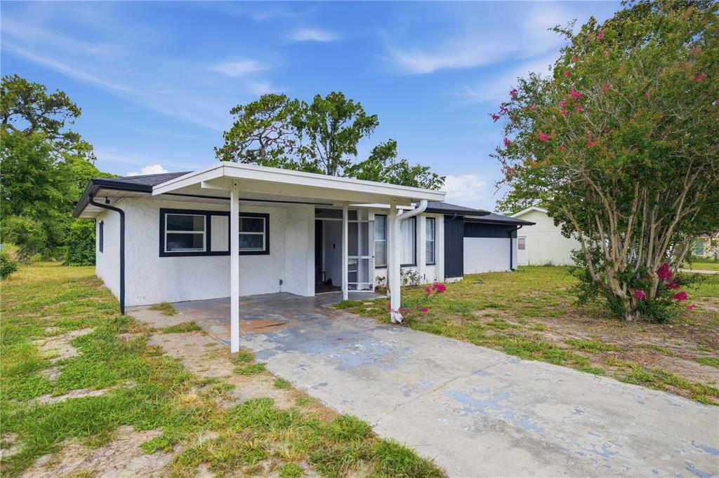 A single-story house with a white stucco exterior, a carport, and a concrete driveway — 477 SPRING LANE, OCALA, FL