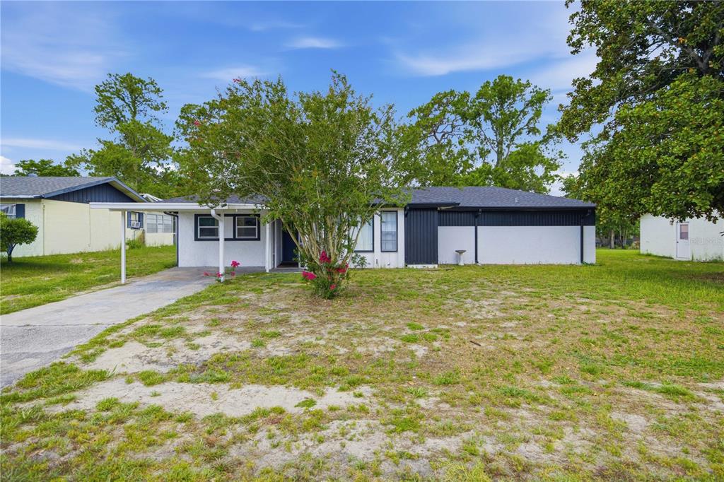 A single-story house with a white exterior, black trim, and a carport on a lawn — 477 SPRING LANE, OCALA, FL