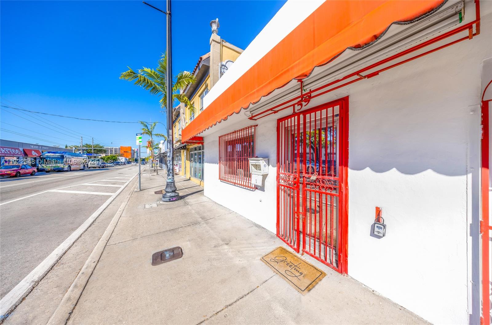 A white building exterior features a red metal security gate, orange awning, and sidewalk — 159 NW 36th St, Miami FL 33127, MIAMI, FL