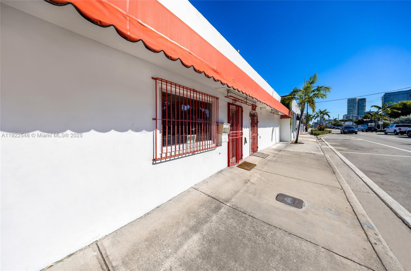 A white building exterior features a red awning, window security bars, and a red door — 159 NW 36th St, Miami FL 33127, MIAMI, FL
