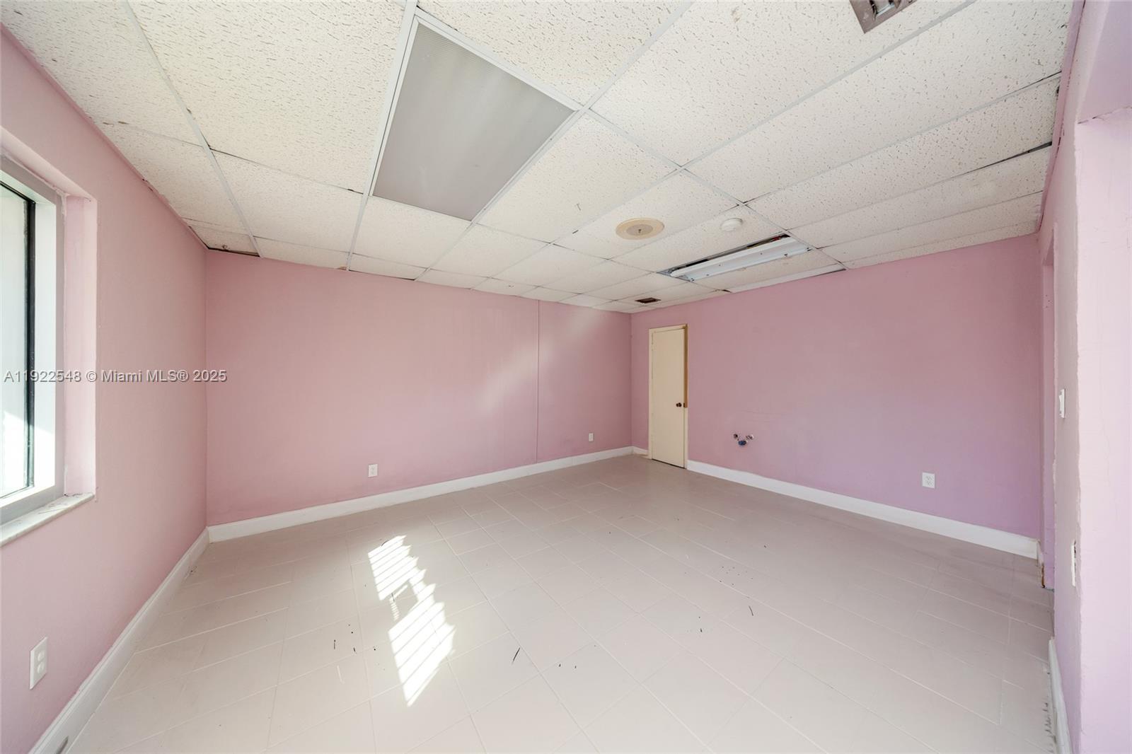 An empty room features pink walls, a drop ceiling, and light-colored tile flooring — 159 NW 36th St, Miami FL 33127, MIAMI, FL