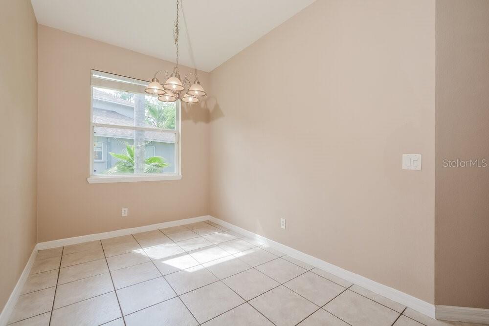 An empty dining area features beige walls, light-colored tile flooring, and a hanging chandelier — 1814 MADISON IVY CIRCLE, APOPKA, FL