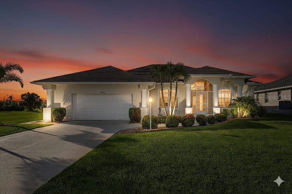 A single-story house with a white exterior, a two-car garage, and palm trees at dusk — 15626 MEACHAM CIRCLE, PORT CHARLOTTE, FL