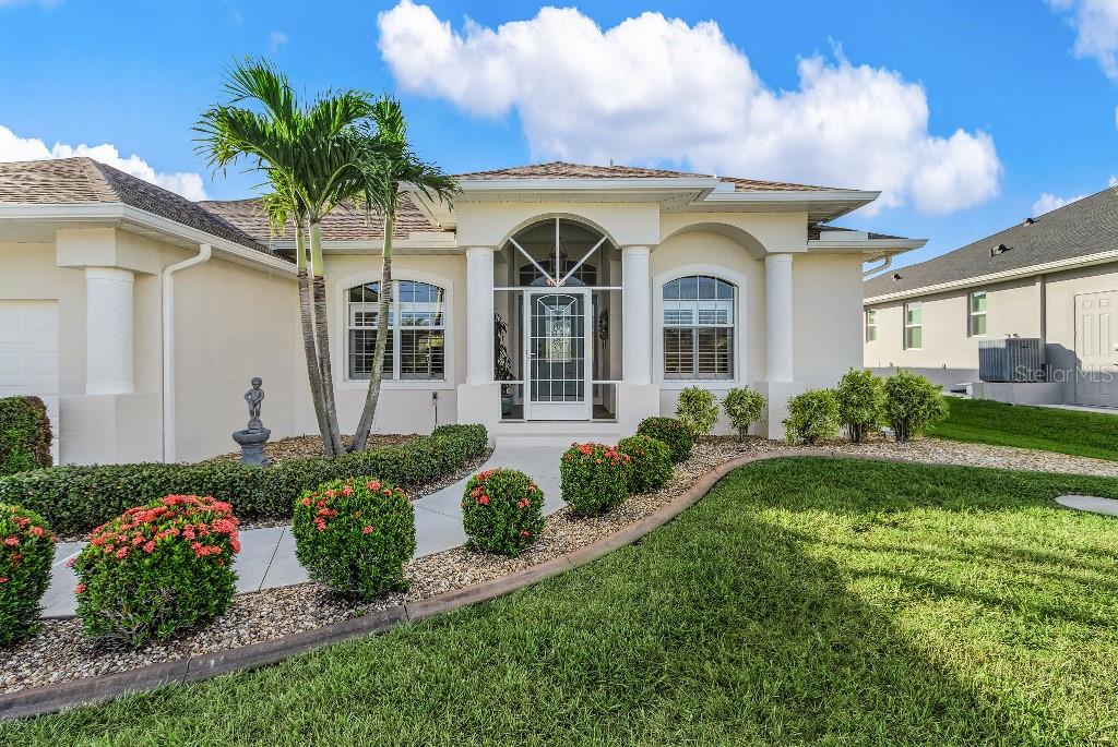 A single-story house with a beige stucco exterior, arched entryway, and a landscaped front yard — 15626 MEACHAM CIRCLE, PORT CHARLOTTE, FL