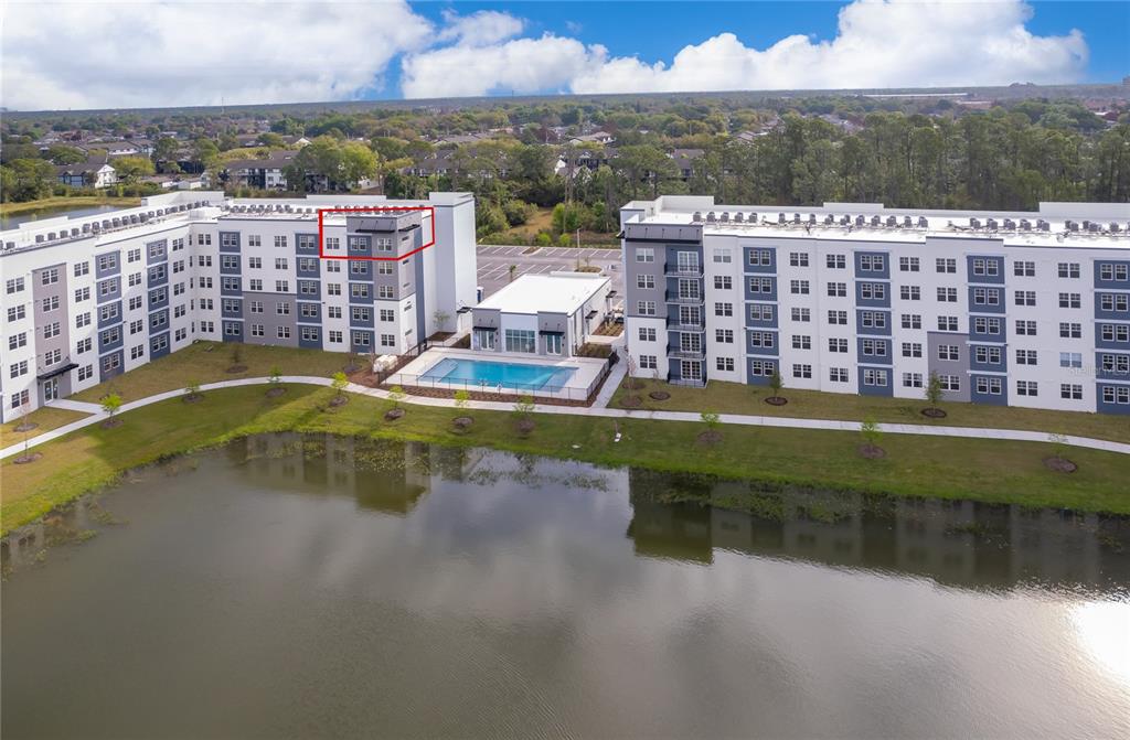 An aerial view shows two large apartment buildings with a pool and a pond — 5579 MILLENIA PARK BLVD UNIT 521, ORLANDO, FL