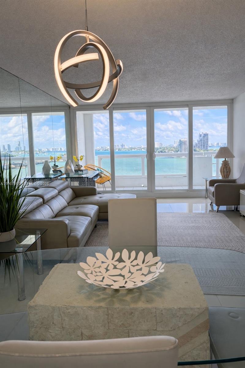 A living and dining area features a modern light fixture, beige sofa, and balcony views — 1717 N Bayshore Dr # 1132, Miami FL 33132, MIAMI, FL