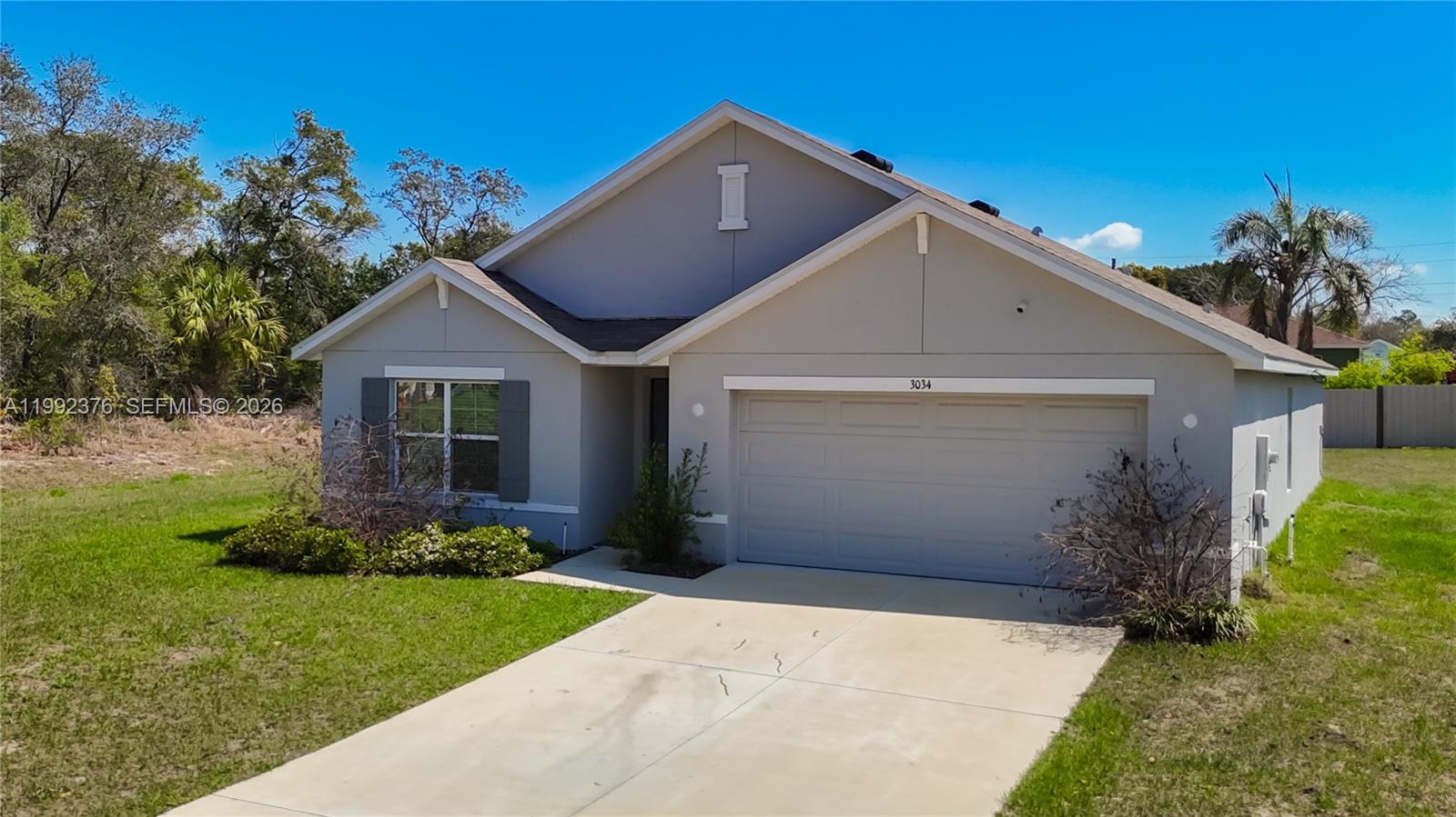A single-story house with a gray exterior, a two-car garage, and a concrete driveway — 3034 Rim Dr, Spring Hill FL 34609, SPRING HILL, FL