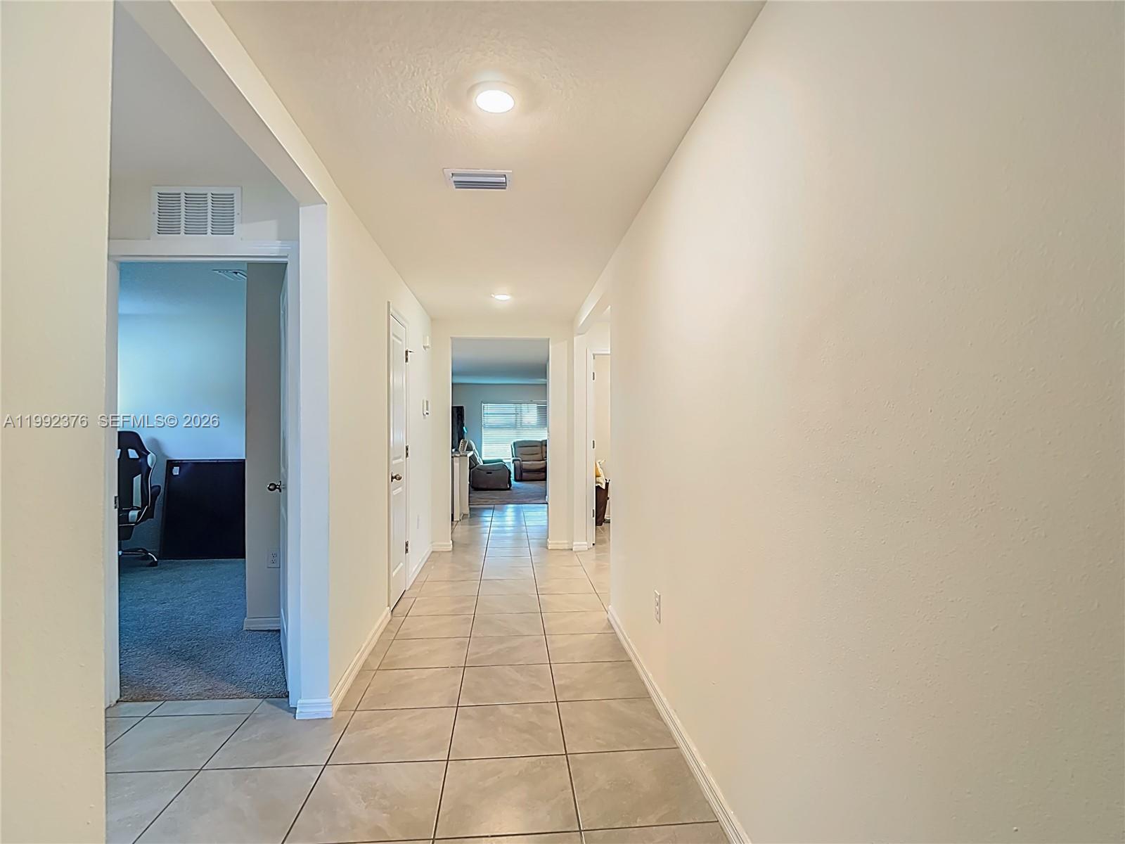 A tiled hallway leads to a living area with light-colored walls and recessed lighting — 3034 Rim Dr, Spring Hill FL 34609, SPRING HILL, FL