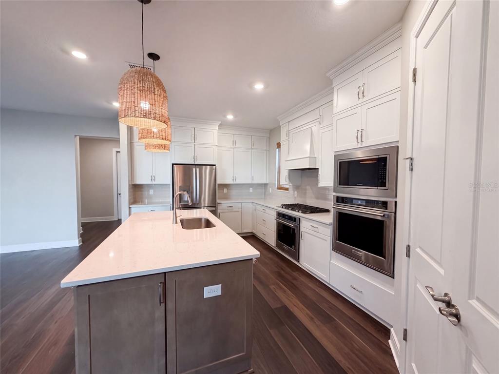 A kitchen features white cabinetry, a gray island with a sink, and stainless steel appliances — 15173 WILLOW RIDGE DRIVE, MONTVERDE, FL