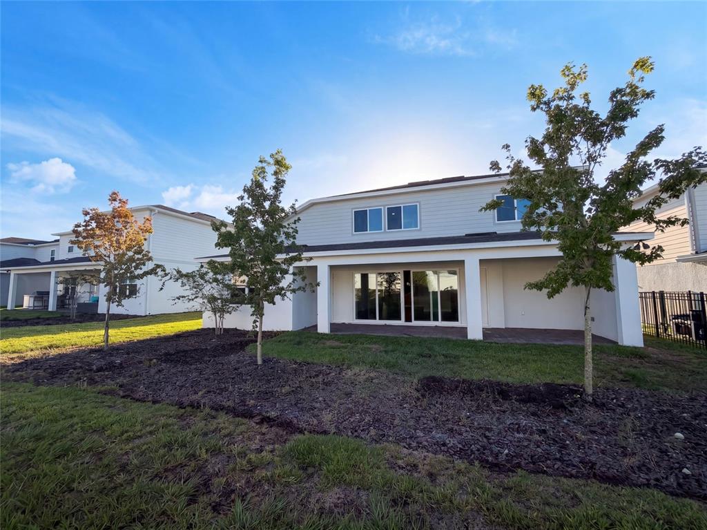 The exterior of a two-story house features a covered patio and a grassy backyard — 15173 WILLOW RIDGE DRIVE, MONTVERDE, FL