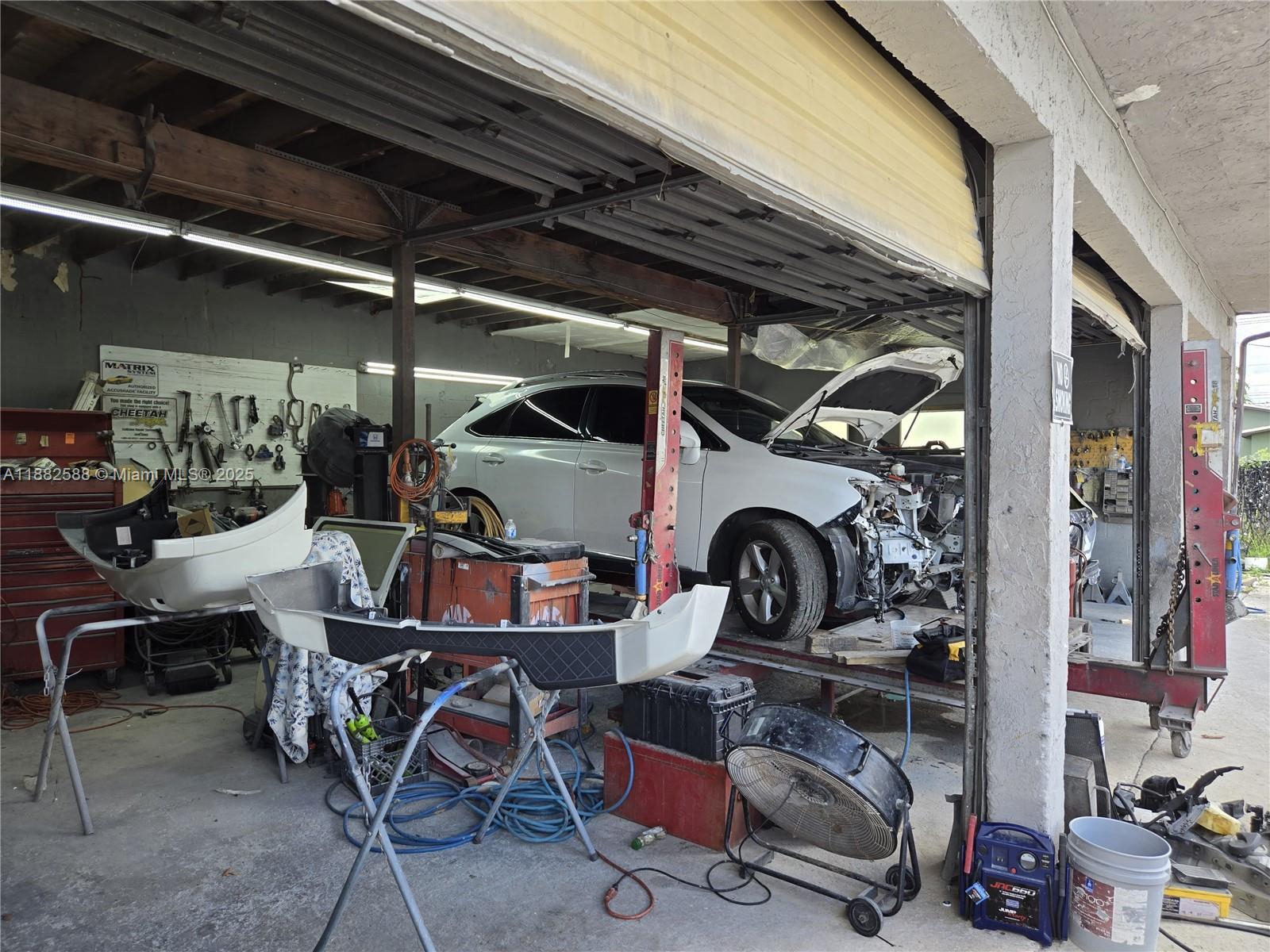 A white SUV with its hood open sits inside an auto repair garage workshop — 5314 Pembroke Rd, West Park FL 33021, WEST PARK, FL