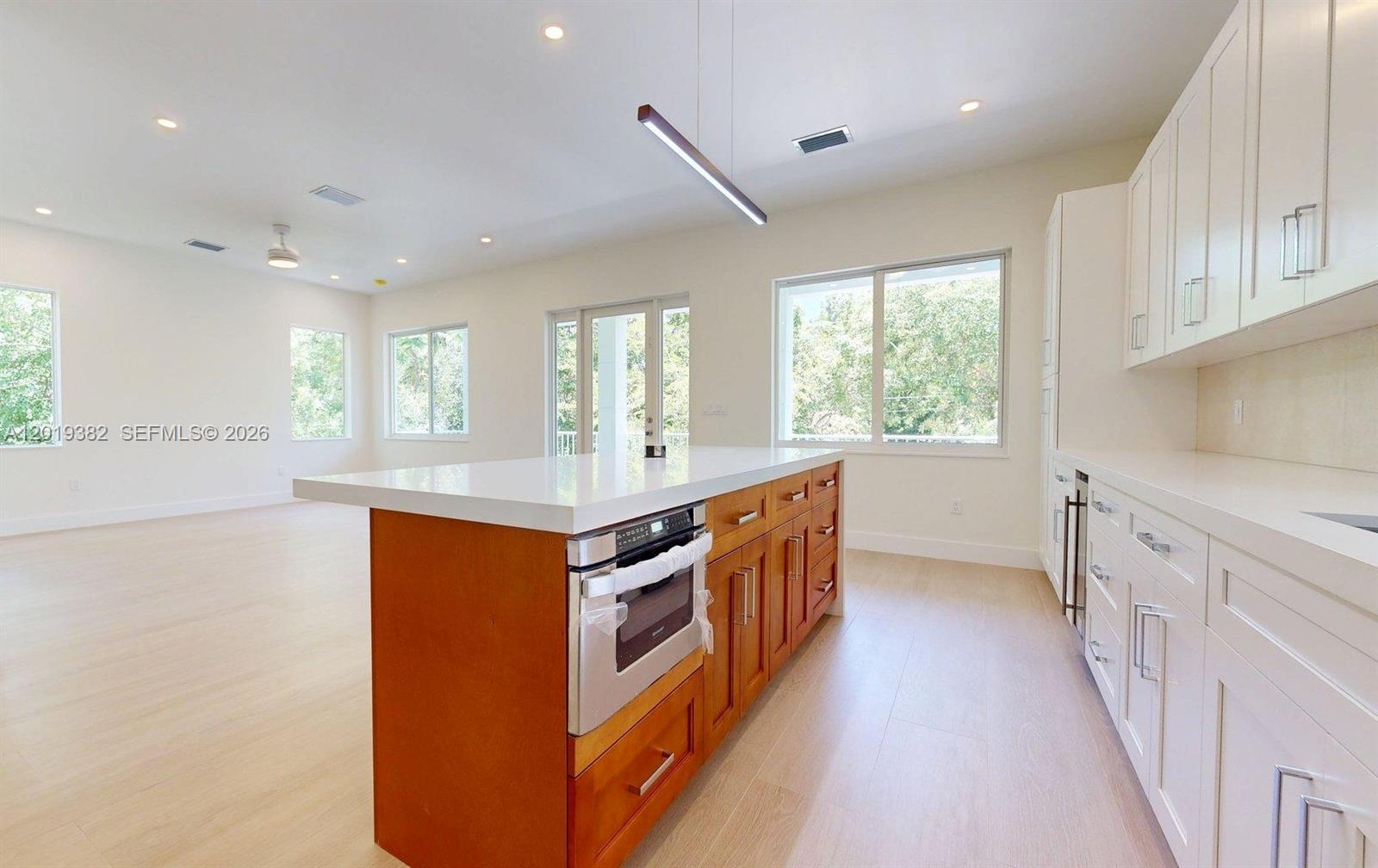 A kitchen features a wood-toned island with a built-in microwave and white perimeter cabinetry — KEY LARGO, FL