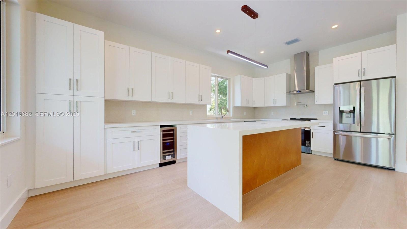 A modern kitchen features white cabinetry, a wooden island, and stainless steel appliances — KEY LARGO, FL