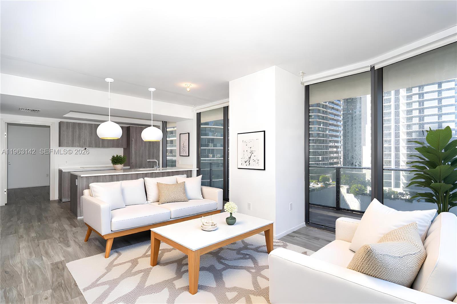 A modern living room features white sofas, a wooden coffee table, and an open kitchen — 801 S Miami Ave # 1409, Miami FL 33130, MIAMI, FL