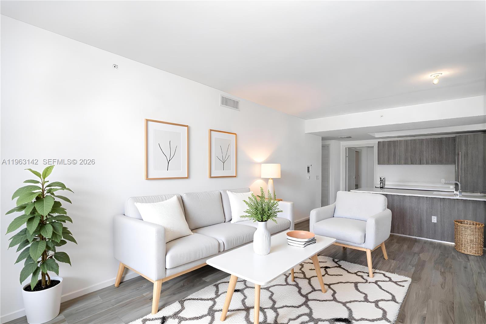 A living room features a light gray sofa, an armchair, and a white coffee table — 801 S Miami Ave # 1409, Miami FL 33130, MIAMI, FL