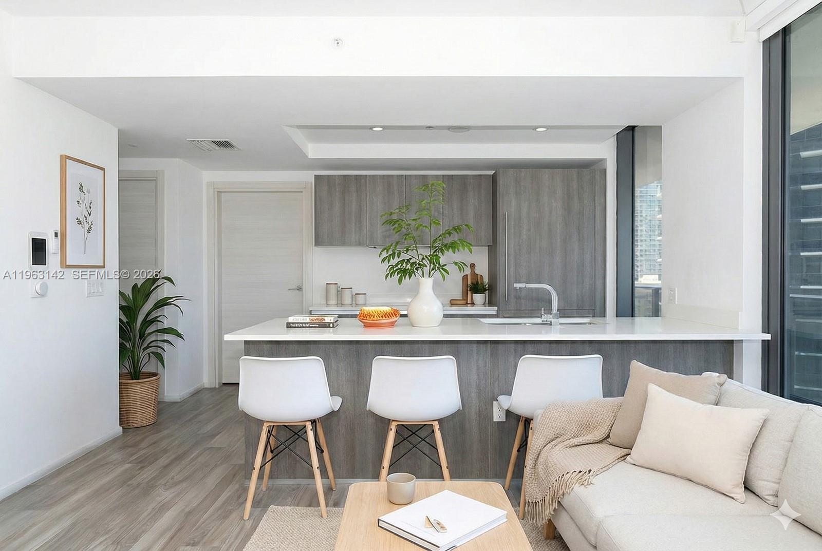 A modern kitchen features a white island with three white chairs and grey cabinetry — 801 S Miami Ave # 1409, Miami FL 33130, MIAMI, FL