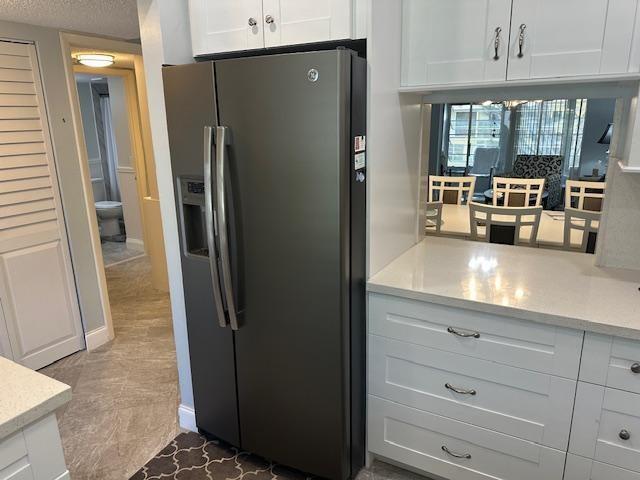 A kitchen features a dark gray refrigerator, white cabinetry, and a view into a dining area — 7410 NW 1st Street # 207, Margate FL 33063, MARGATE, FL