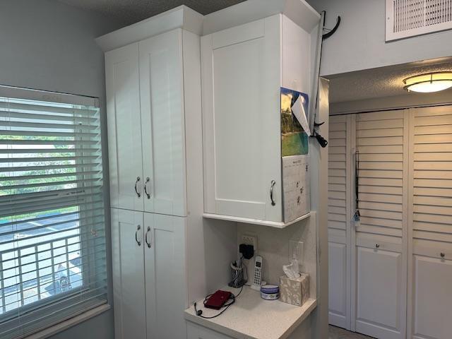 A kitchen area features white cabinetry, a small countertop workspace, and louvered closet doors — 7410 NW 1st Street # 207, Margate FL 33063, MARGATE, FL