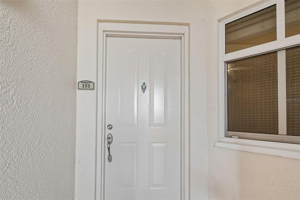 A white front door with a number 151 plaque sits beside a window — 12033 GANDY BOULEVARD N UNIT 151, ST PETERSBURG, FL