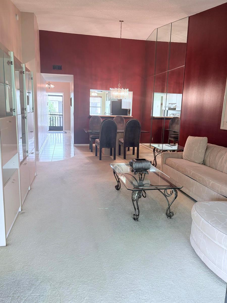 A living and dining area features deep red walls, mirrored panels, and light-colored carpeting — 7831 Willow Spring Drive # 526, Lake Worth FL 33467, LAKE WORTH, FL
