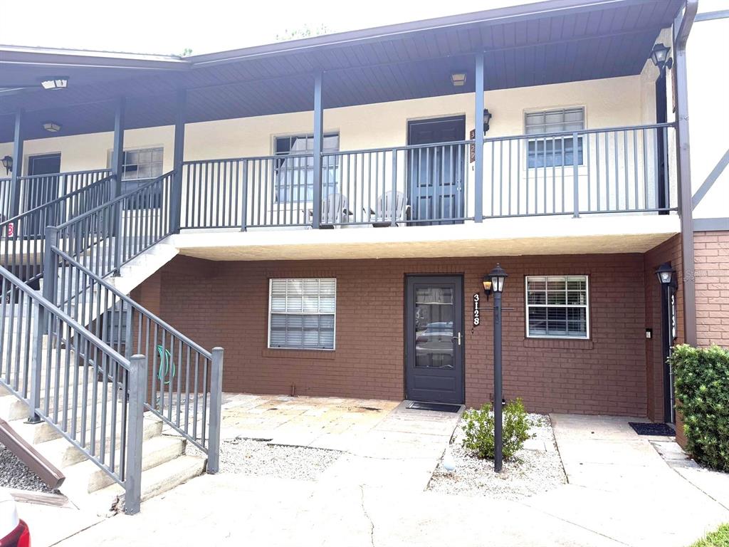 A two-story apartment building exterior features a brown brick lower level and a balcony — 3128 SIR HAMILTON CIRCLE UNIT 4, TITUSVILLE, FL
