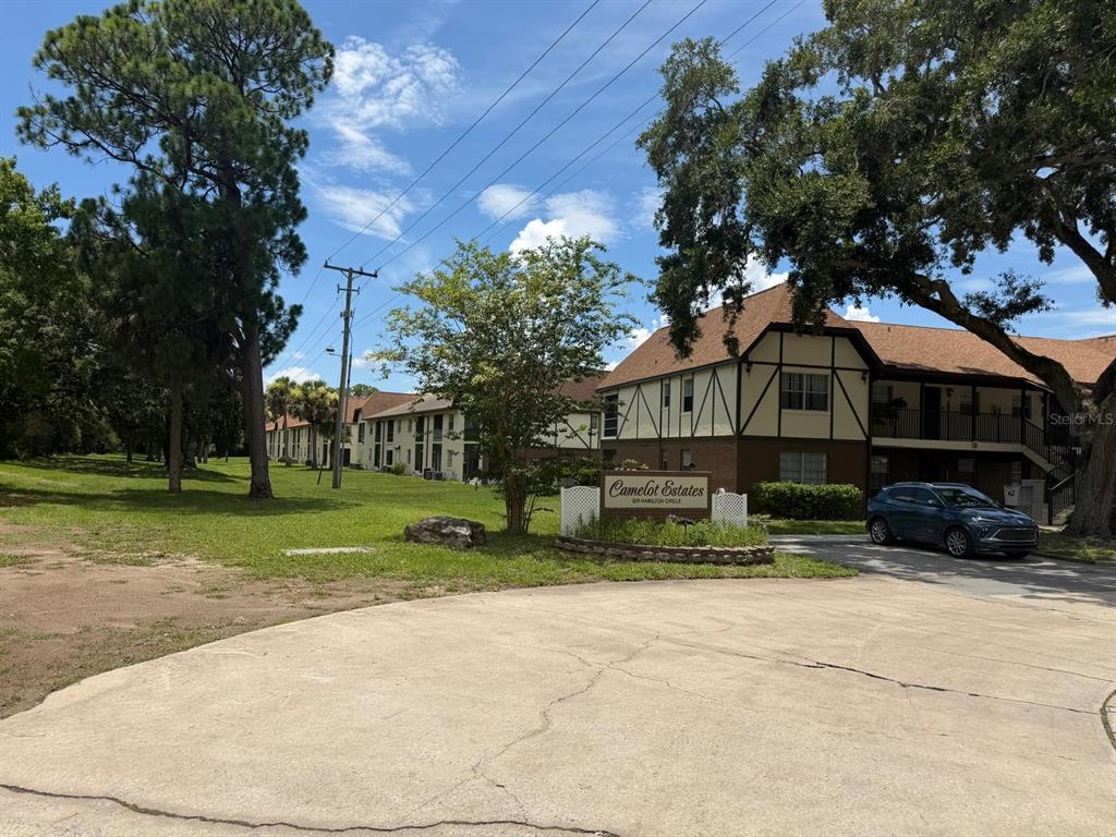The exterior of the Camelot Estates apartment complex features a sign and a parked car — 3128 SIR HAMILTON CIRCLE UNIT 4, TITUSVILLE, FL