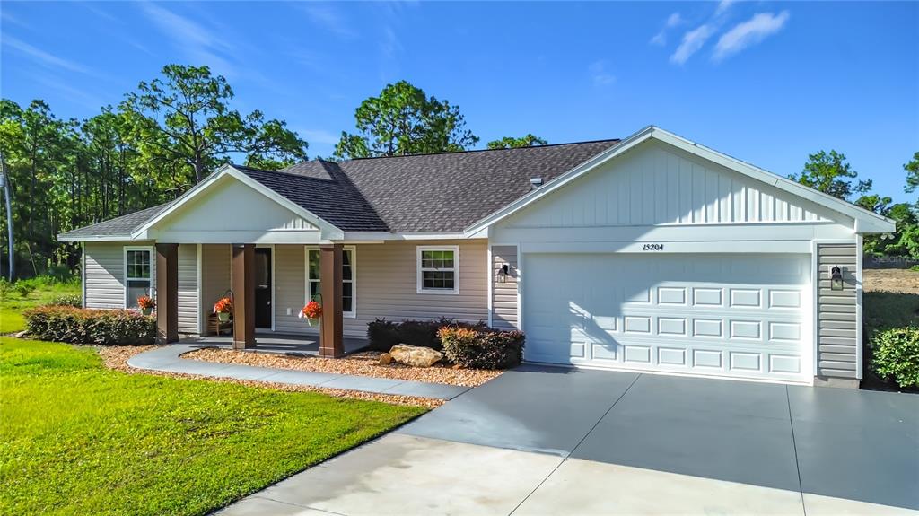 A single-story house with light siding, a dark shingled roof, and a two-car garage — 15204 GANSTER DRIVE, BROOKSVILLE, FL