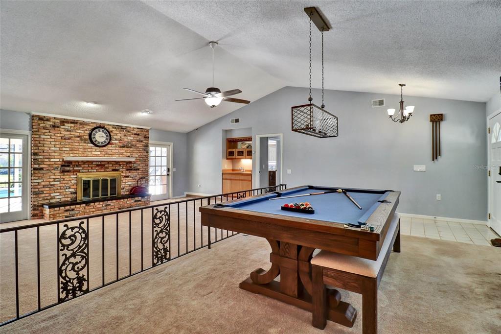 A game room features a pool table, a brick fireplace, and a metal railing — 4318 WOODTREE LANE, ORLANDO, FL