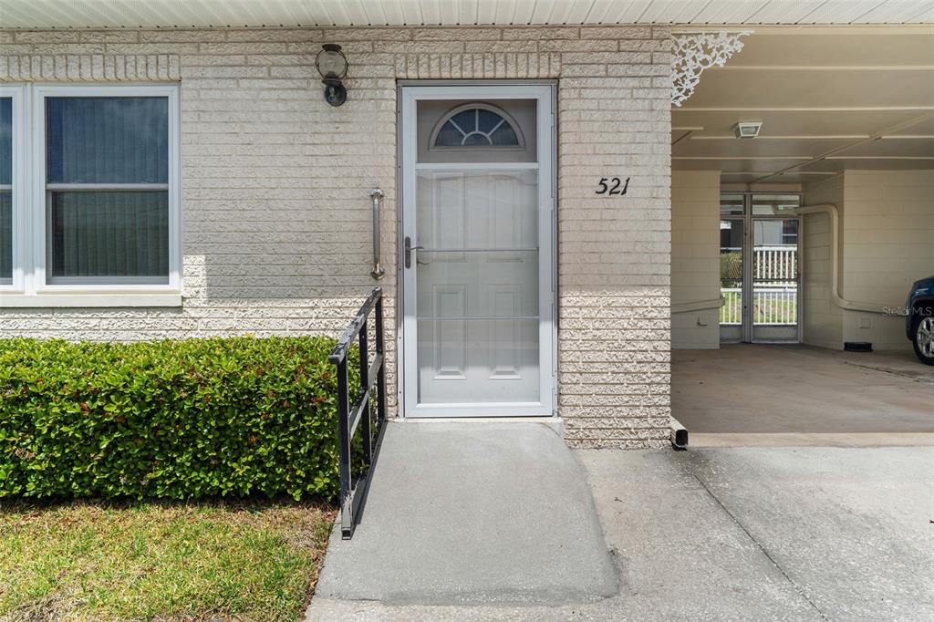 A concrete ramp leads to the front door of a brick home with a carport — 12400 PARK BOULEVARD UNIT 521, SEMINOLE, FL