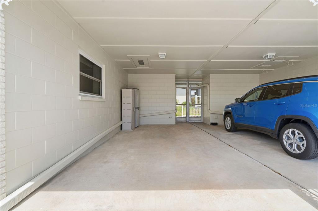 A covered carport with concrete block walls, a concrete floor, and a parked blue SUV — 12400 PARK BOULEVARD UNIT 521, SEMINOLE, FL