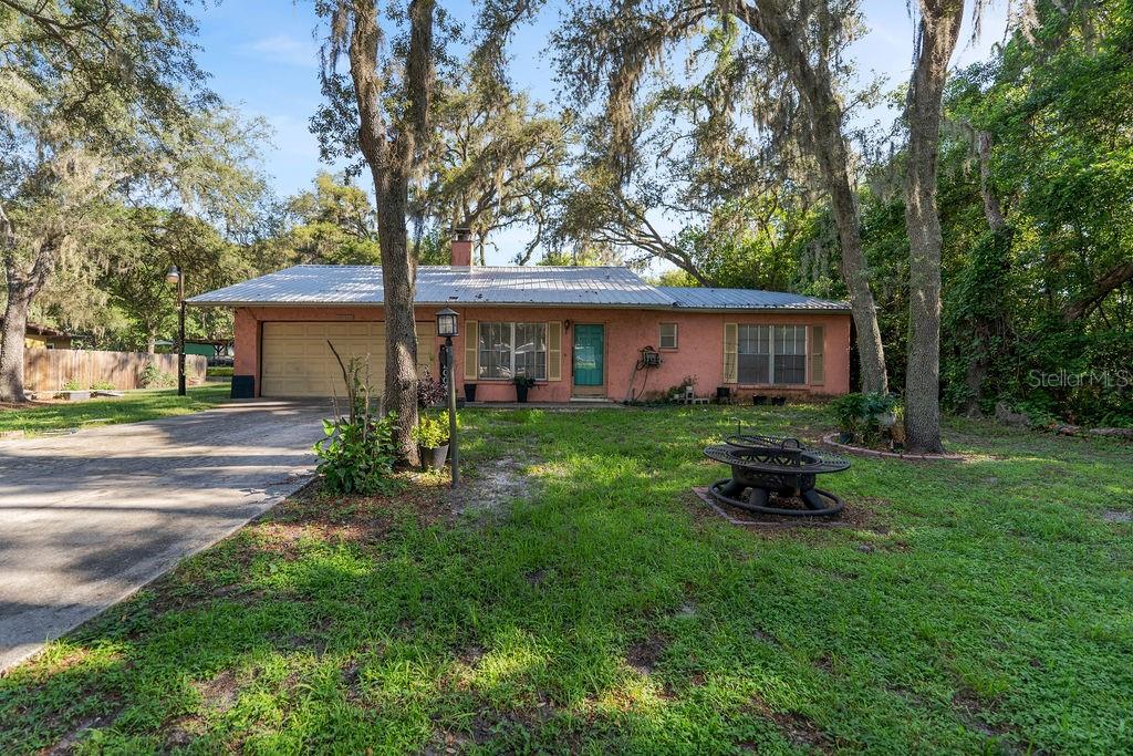 A single-story pink house with a metal roof and a two-car garage — 38213 PALM GROVE DRIVE, ZEPHYRHILLS, FL