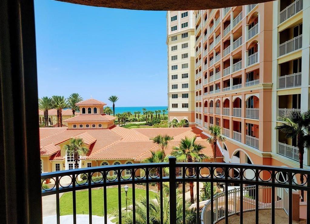 A balcony view overlooking a resort-style building, palm trees, and the ocean in the distance — 200 OCEAN CREST DRIVE UNIT 231, PALM COAST, FL