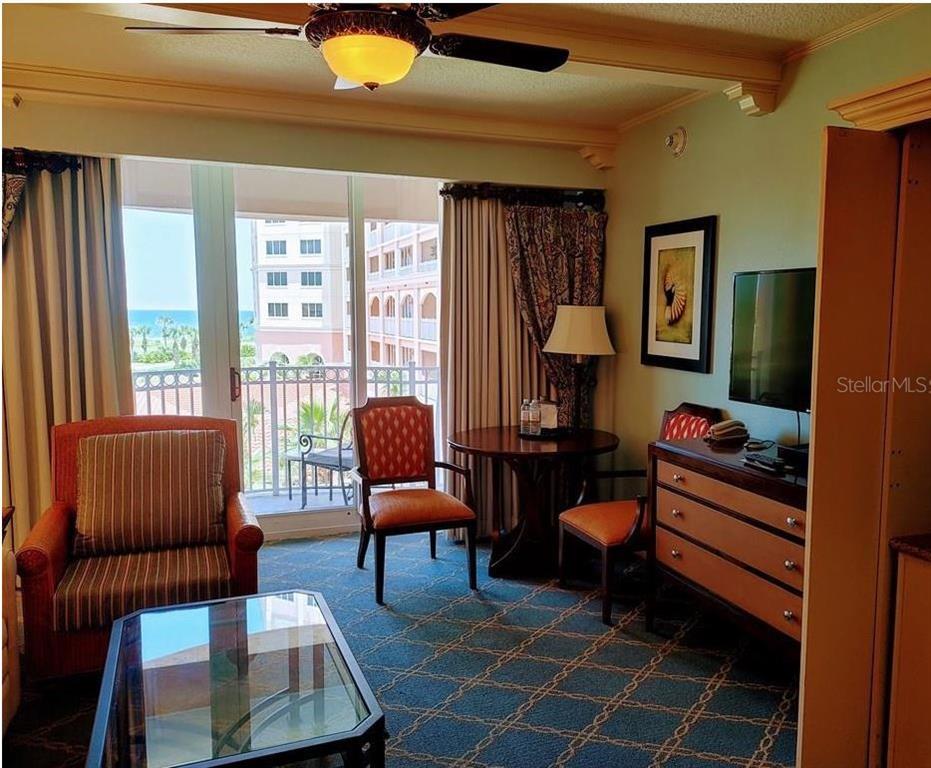 A hotel room with a balcony, seating area, television, and blue patterned carpet — 200 OCEAN CREST DRIVE UNIT 231, PALM COAST, FL