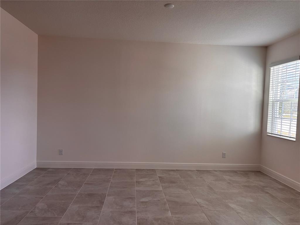 An empty room features light-colored walls, tile flooring, and a single window with blinds — 1880 ROSS HAMMOCK AVENUE, GROVELAND, FL