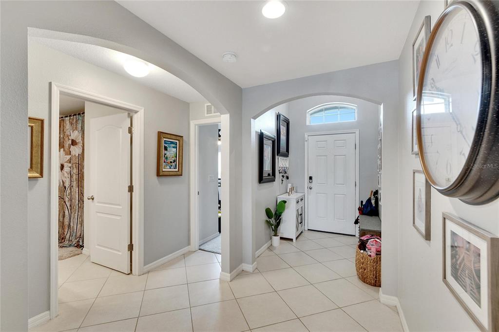 An entryway features tile flooring, arched doorways, a white front door, and wall-mounted decor — 11355 LELAND GROVES DRIVE, RIVERVIEW, FL